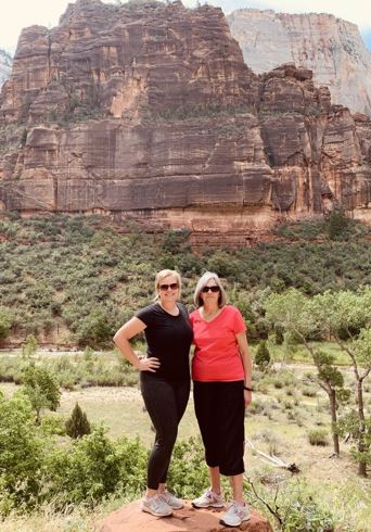 Morgan and her mom standing in from of a forest that has a mountian in the backgound